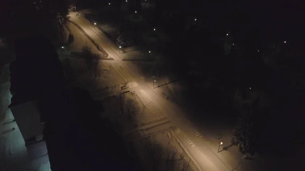 Vista aérea de lâmpadas de rua elétricas acesas no parque de inverno noturno coberto de neve. Clipe. Bela vista do parque de inverno à noite — Fotografia de Stock