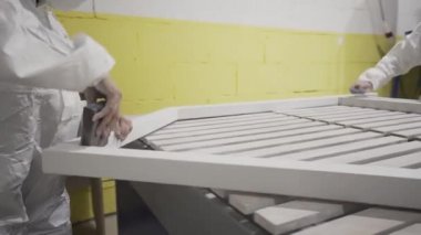 Moskova, Rusya - Nisan, 2019: İşçiler fabrikada çerçeve cilalı. Eylem. Beyaz tulum işçilerin iki kadın ahşap ürünlerin işlenmesinde pencere beyaz çerçeve eziyet