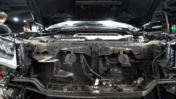 Assembling hood of car in automotive plant. Action. Close-up of details of front of car on background of mechanics in overalls assembled at modern enterprise auto assembly — Stock Video