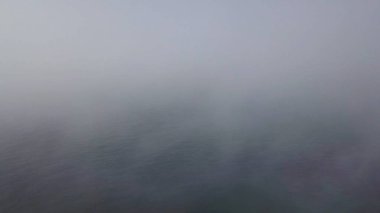 Su üzerinde mavi bulutlu gökyüzüne sevgi dolu çift ile uçurumun üzerinde uçan. Eylem. Bulutların arkasına gizlenmiş ufukla deniz manzarasının havadan görünümü.