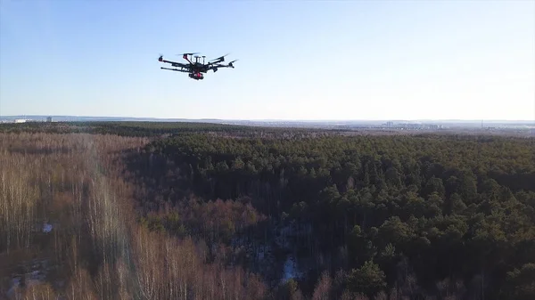 Aerial for the drone camera flying in the sky above deciduous and coniferous forest on blue sky background. Clip. Spinning quadcopter blades, slow motion. — Stock Photo, Image