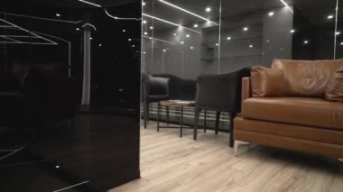 Kanepe ve siyah cam ile modern pahalı iç. Eylem. Arka plan siyah sercal duvarlar ve parlak yapay aydınlatma koltuklar ve deri kanepe ile dar alan