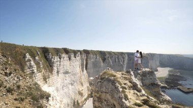 Beyaz kayalar ve mavi deniz ve berrak gökyüzü ile plaj arka planda öpüşme Loving çift. Eylem. Beyaz kayaların güzel manzara arka plan üzerinde öpüşme tatilde Turist çift