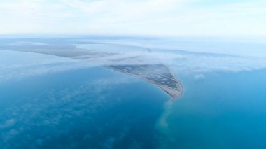 Gökyüzü ufku arka planda deniz arasında sahil üst görünümü. Atış. Mavi deniz ve üçgen kıyıüzerinde bulutlar arasında gökyüzünde en yüksek görünümü
