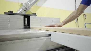 İşçinin yakın çekim ahşap işleme makinesiüzerinde ahşap tahta tutar. Eylem. Eldiven işçi ahşap için modern işletmede otomatik makine ahşap tahta süreçleri