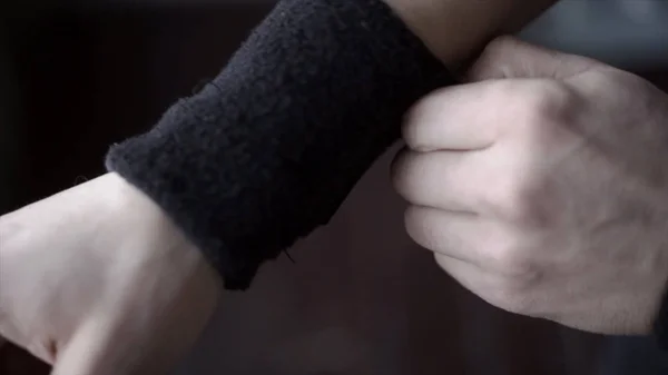 Der Sportler trägt schwarze Armbänder. Aktion. Nahaufnahme des Athleten passt seine Armbänder an den Händen an, um das Handgelenk beim Sport nicht zu verletzen — Stockfoto