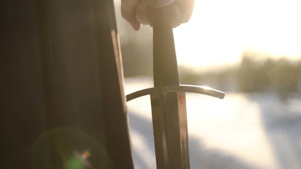 Homem de fato medieval a segurar espada. Acção. Close-up de homens mão em terno medieval segurando punho espada no fundo da luz solar. Vista épica do herói medieval — Fotografia de Stock