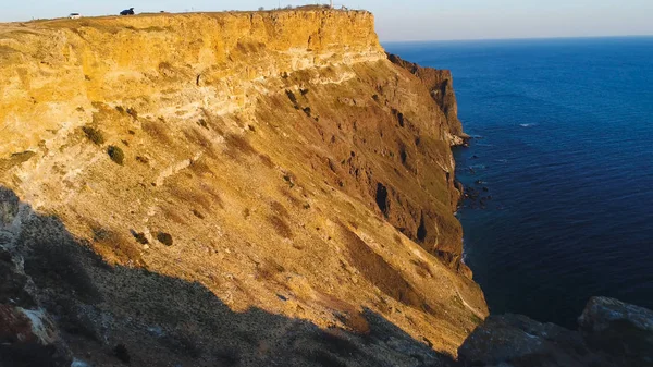 Vista dall'alto della scogliera costiera con mare azzurro al tramonto. Gli hanno sparato. Bella vista della luce dorata del tramonto sulle scogliere rocciose della costa del mare con acque blu — Foto Stock