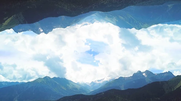 Panoráma a hegyekre tükörkép hatással. Lövés. Gyönyörű felülnézet a zöld völgyek hegyek háttér kék felhős égbolt tükörképe invertált világ — Stock Fotó