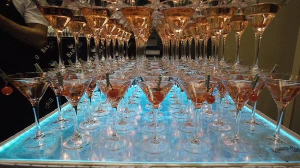 Viele Gläser für Martini mit Alkohol stehen in der Bar auf dem Tisch. Aktion. Berge von Weingläsern Martini mit alkoholischen Getränken und Kirschen für Veranstaltung Barkeeper Show vorbereitet — Stockfoto