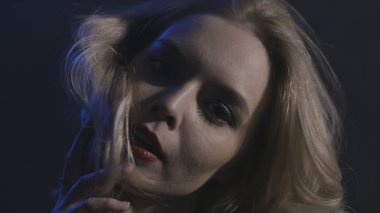 Yeşil gözleri ve şehvetli dudakları koyu arka plan, baştan çıkarma kavramı izole ile genç bayan için yakın. Eylem. Baştan çıkarıcı sarışın kadın saçlarına dokunmadan ve düz görünümlü.