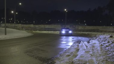 Araba geceleri boş karlı yolda park etti ve farları açık. Eylem. Karanlıkta yolda duran neon farlar ile Yalnız araba.