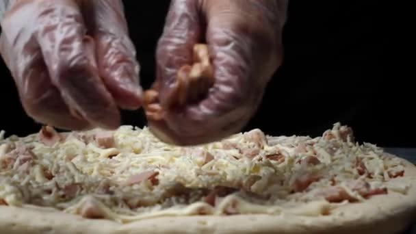 Primo piano di capo in guanti di silicone bianco fare la pizza e l'aggiunta di pezzi tagliati salsicce sulla pasta della pizza. Cornice. Cucina tradizionale italiana — Video Stock