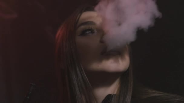 Beautiful sexy brunette girl with bright makeup exhaling smoke from her mouth on black background, bad habits concept. Action. Portrait of young woman smoking hookah. — Stock Video