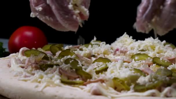 Chiudere per le mani in guanti da cucina cospargere una pizza con formaggio grattugiato, concetto di cibo italiano. Cornice. Uno chef mette il parmigiano sulla pizza con i pezzi di cetriolo sottaceto . — Video Stock