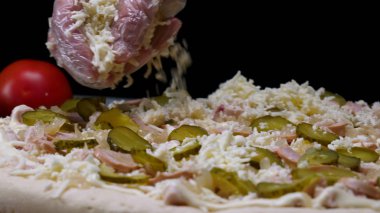 Pişirme eldivenelleriçin yakın rendelenmiş peynir, İtalyan gıda kavramı ile bir pizza serpin. Çerçeve. Bir şef salatalık turşusu parçaları ile pizza parmesan peyniri koyarak.