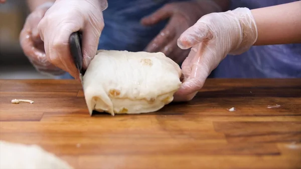 Vrouw in koken handschoenen snijden bladerdeeg met rozijnen in stukjes, voedsel concept. Stock footage. Close-up voorhanden snijden vers deeg met een speciaal mes. — Stockfoto