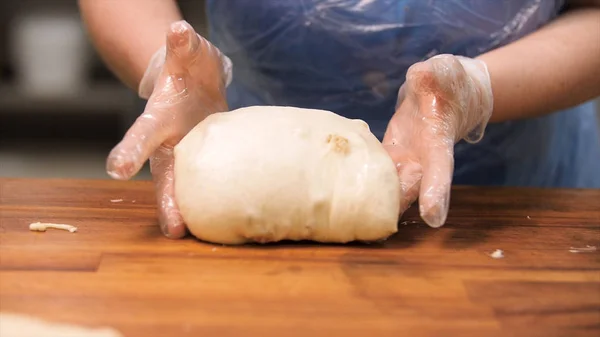 レーズンと生地で作業中の菓子のためのクローズアップ。ストック映像。大きなペストリーを取り、生地からパンを作る調理手袋で女性の手のためのクローズアップ. — ストック写真