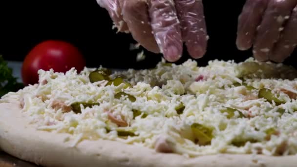 Chiudere per il processo di preparazione della pizza da mani di chef isolate su sfondo nero. Cornice. Allineare lo strato di formaggio sulla pizza con i pezzi di cetriolo sottaceto . — Video Stock