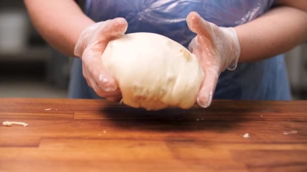 Cerrar para el confitero en el trabajo con la masa cruda con pasas. Imágenes de archivo. Cierre para las manos de la mujer en guantes de cocina tomando un gran pedazo de masa, haciendo bollos de masa . — Vídeos de Stock