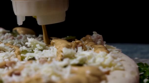 Hautnah für einen Koch, der der frischen Pizza vor dem Backen Käsesauce hinzufügt, italienische Küche. Rahmen. traditionelles italienisches Rezept einer Pizza, die durch die Sauce gegossen wird. — Stockvideo