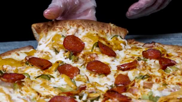 U ruky si můžete vyzvednout kousek chutného feferonové pizzy, gastronomie. Rámeček. Horká Pizza na černém pozadí.