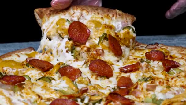 Gros plan pour cueillir à la main une tranche de pizza pepperoni savoureuse, foodporn. Cadre. Pizza pepperoni italienne chaude sur fond noir . — Video