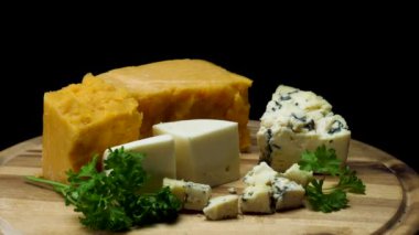 Doğranmış ve siyah arka plan üzerinde izole ahşap tahta üzerinde servis fransız lezzetli yaşlı peynirler için yakın. Çerçeve. Çedar, parmesan ve maydanoz lu mavi peynir parçaları.
