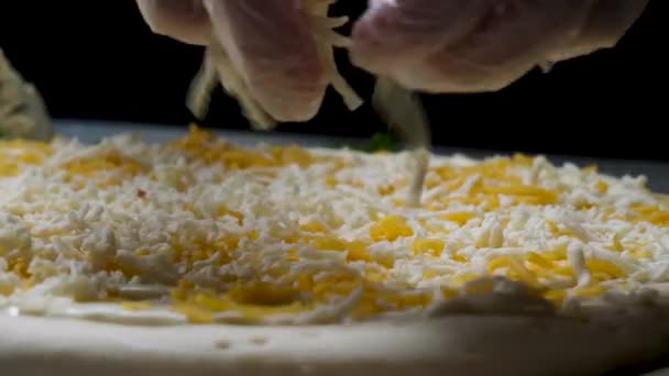 Fermer pour cuisiniers mains dans des gants de cuisine mettre du fromage sur la pizza Quatre fromages. Cadre. Chef ajoutant les ingrédients à la pizza, la production et la livraison des aliments . — Video