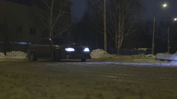 Auto invernale alla deriva nella strada della città di notte, concetto di motorsport. Azione. Un veicolo passeggeri che va in slittamento su una strada innevata . — Foto Stock