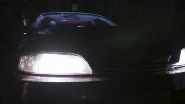 Gece açık park edilmiş bir binek otomobilin farları için kapatın, araba detayları kavramı. Eylem. Karanlıkta duran ve bir sürücünün araba ışıklarını yakarak durması.