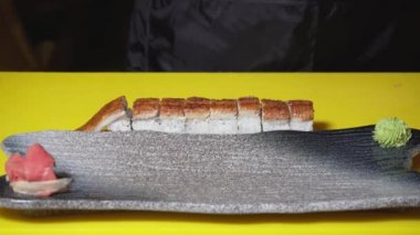 Şef gemiye suşi rulosu koyar. Çerçeve. Şefin yakın çekim restoranda hizmet için düz plaka üzerine suşi rulo koyar. Oryantal restoranda e-paralı suşi ruloları servis edilmektedir