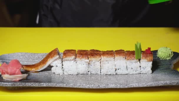 Chef decorando rollos de sushi para servir en el restaurante. Una trampa. Primer plano de chef profesional pone un puñado de caviar rojo en rollos de sushi para una hermosa porción — Vídeo de stock