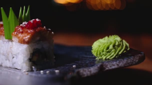 V těsné blízkosti nádherně zdobených Suši se nacházejí na talíři s wasabi. Rámeček. Profesionálně připravené a zdobené Suši s úhořem v drahé restauraci — Stock video