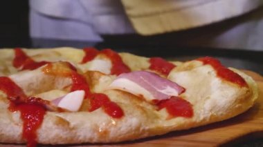 Şef pizzaya jambon dilimleri koyuyor. Çerçeve. Jambon ve salam ile yakın çekim pişirme sulu lezzetli İtalyan pizza. Eldiven giyen şef pizzanın üzerine et dilimleri koyuyor