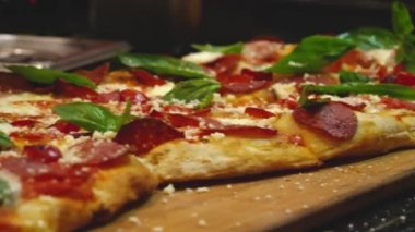 Fesleğen yaprakları ile pişmiş pepperoni pizza yakın çekim. Çerçeve. İtalyan restoranında veya pizzacıda pişirilen sulu kokulu pizza. Ağzını sulayan pizza. İtalyan mutfağı