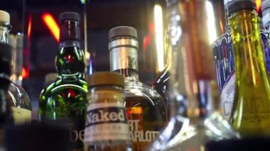 Barda alkol çeşitlerinin yakın çekim. Çerçeve. Renkli cam şişeler parlak lambalar arka plan üzerinde bar sayacı üzerinde durmak. Gece pub alkol farklı türleri