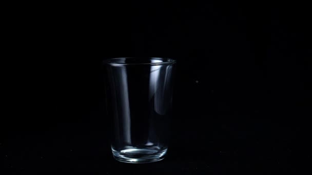 Transparent glass cup on black isolated background. Frame. Glass for tea stands empty glint from faint white light on black background — Stock Video