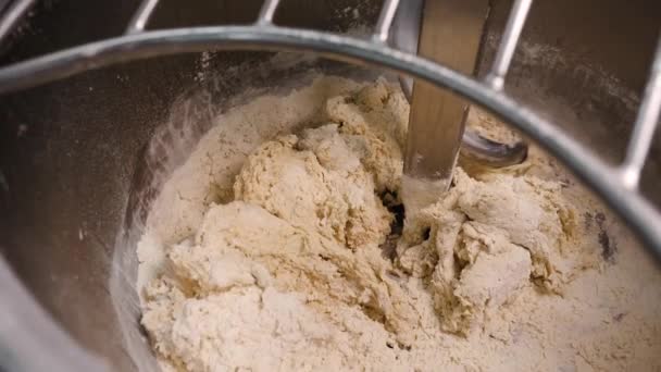 Close-up of kneading dough in mixer with flour. Stock footage. Small pinches of flour are added to mixing dough in industrial mixer in bakery — Stock Video