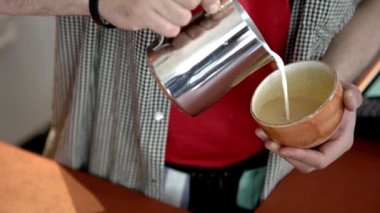 Kahve üzerine çizim yapan profesyonel baristayakın çekim. Madde. Barista sanatı ve kremaile kahve çizim. Beceri baristas ustaca cappuccino üzerine çizimler oluşturmak pitching denir