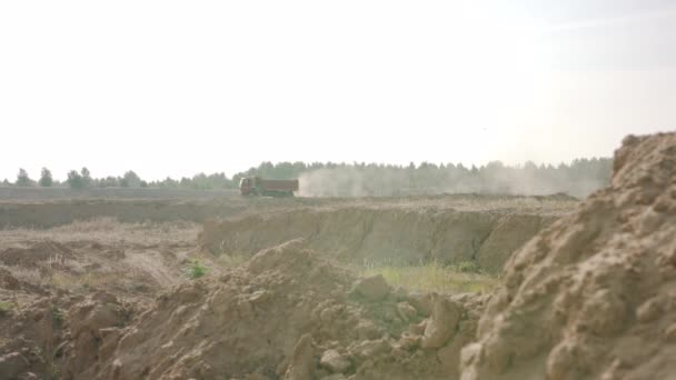 卡车在尘土飞扬的公路上行驶到采石场。现场。在粘土堤的背景卡车行驶在田间公路上留下灰尘痕迹 — 图库视频影像