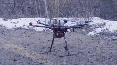 Quadcopter'ın yakın çekimi havalanıyor. Klip. Yeni nesil quadcopter güçlü modeli kalkış için hazırlanıyor zemin üzerinde. Quadcopter kar ile orman arka plan üzerinde