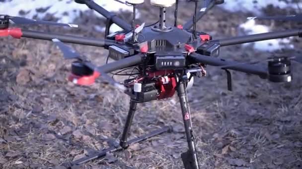 Close-up details van de quadrocopter. Clip. Krachtige quadcopter met een nieuwe generatie professionele camera is klaar voor het opstijgen. Quadcopter is op de grond voor luchtfotografie — Stockvideo