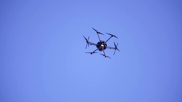 Närbild av Quadcopter flyger i Sky. Klipp. Stor Quadcopter med kraftfulla motorer som flyger på bakgrunden blå himmel. Quadcopter med sex motorer för lång luft — Stockvideo