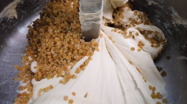 Mikserde kuru üzüm ile hamur yakın çekim. Stok görüntüleri. Fırın için hazırlanan lezzetli endüstriyel hamur işleri. Kuru üzüm büyük miktarda karıştırıcı maya hamuru ile karıştırılır