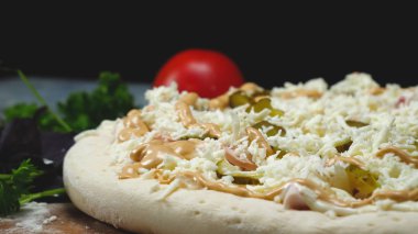 İtalyan pizzası hazırlayan şefin yakın çekim. Çerçeve. Eldivenli profesyonel şef pizzanın üzerine salatalık dilimleri koydu. Siyah izole arka plan üzerinde İtalyan pizza pişirme