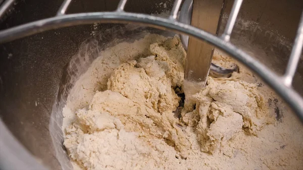 Close-up of kneading dough in production mixer. Stock footage. Spiral kneader kneads fresh dough for baking in bakery