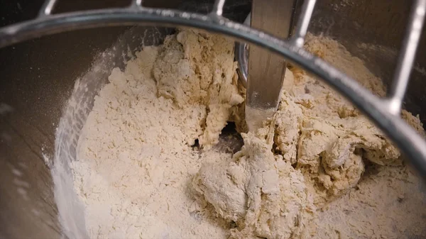 Close-up of kneading dough in production mixer. Stock footage. Spiral kneader kneads fresh dough for baking in bakery