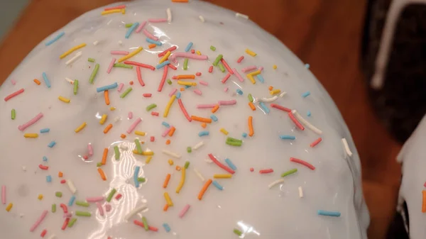 Close-up of glazed easter cakes. Stock footage. Traditional easter cakes covered with white sugar glaze and decorated with rainbow sprinkles — Stock Photo, Image