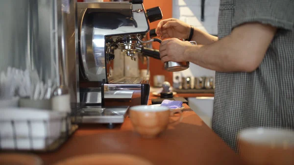 Close-up of professional barista pours coffee from coffee machine. Art. Mastery in management of coffee equipment and coffee brewing machine
